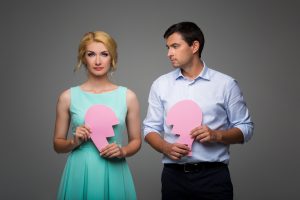 A young couple holding a broken pink heart.