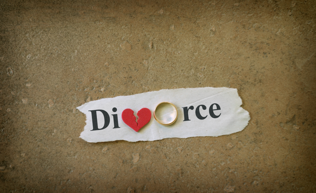 The word divorce with a split heart as the letter V and a wedding band as the letter O